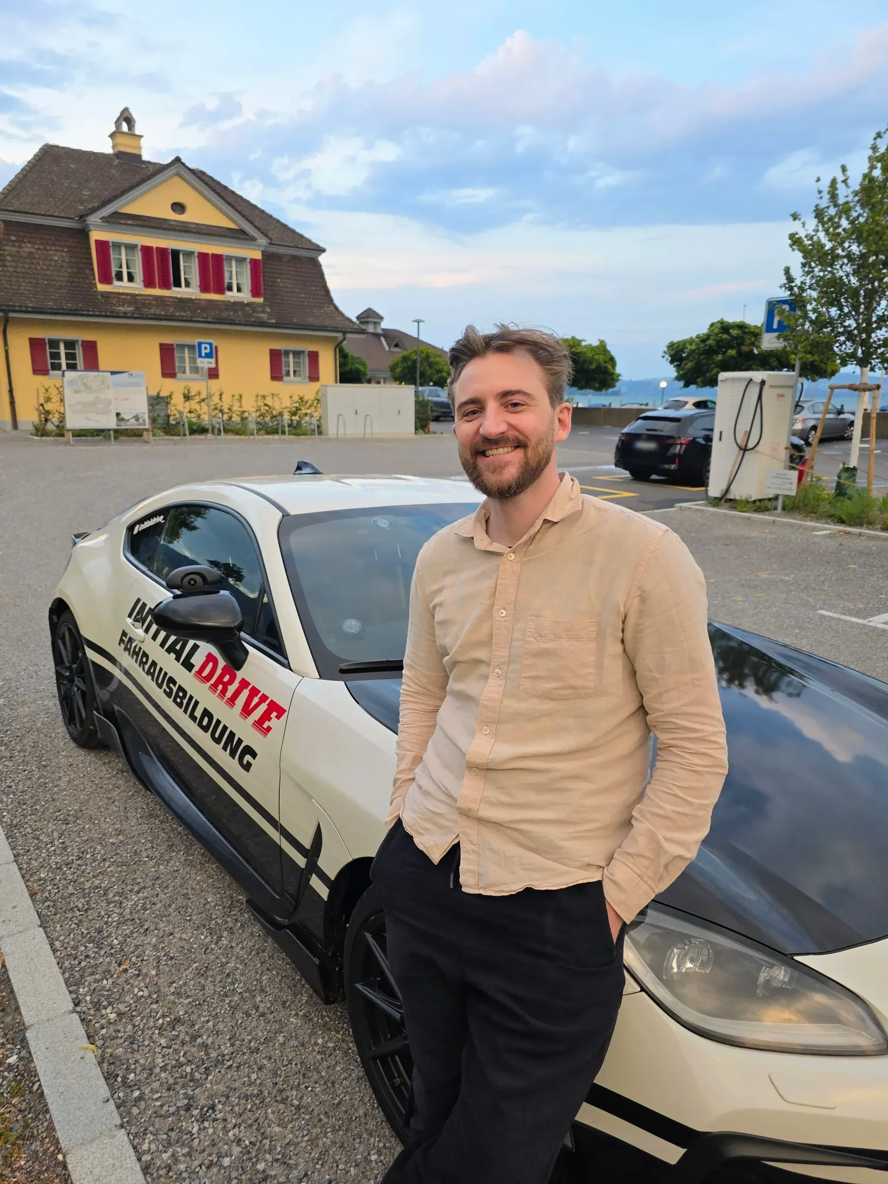 Patrik Stadelmann, Fahrlehrer und Inhaber von Initial Drive, lehnt lächelnd am Toyota GR86 der Fahrschule