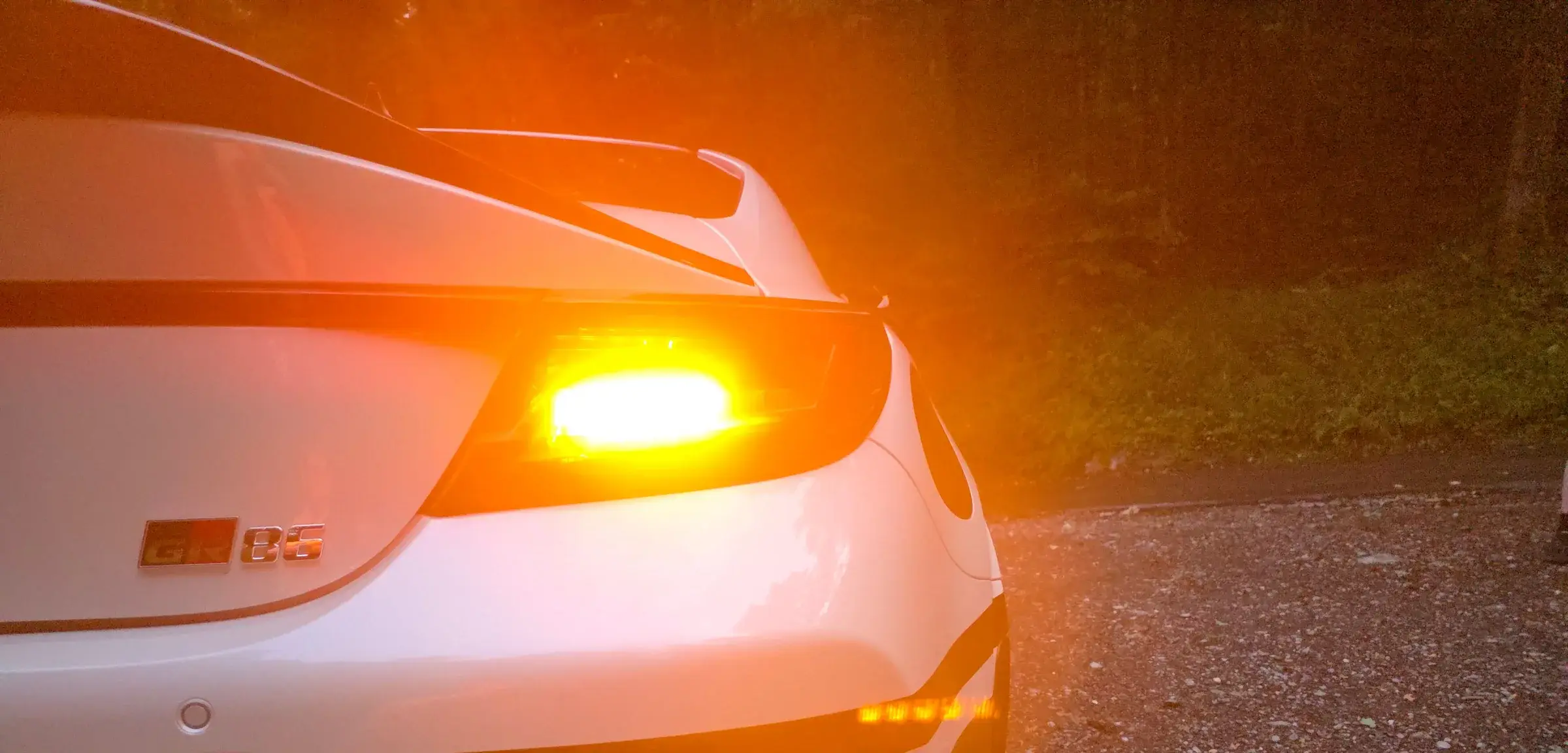 Leuchtender Blinker am Heck des Toyota GR86 von Initial Drive in der Abenddämmerung