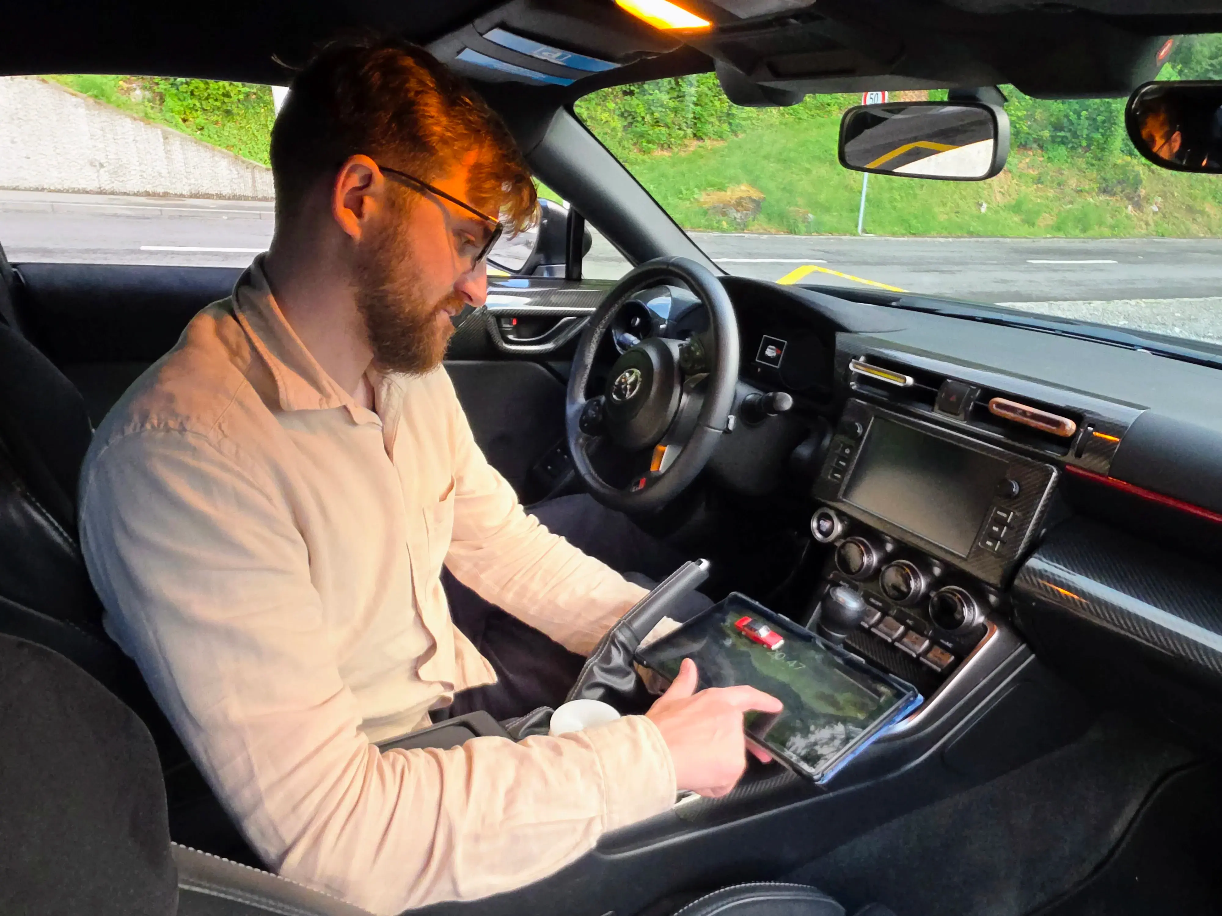 Fahrlehrer Patrik Stadelmann sitzt im Toyota GR86 und arbeitet an einem Tablet – Vorbereitung auf die Kontrollfahrt in Luzern
