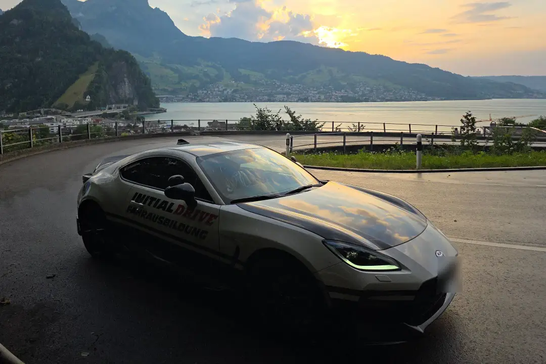 Toyota GR86 der Fahrschule Initial Drive in einer Kehre über dem See bei Sonnenuntergang