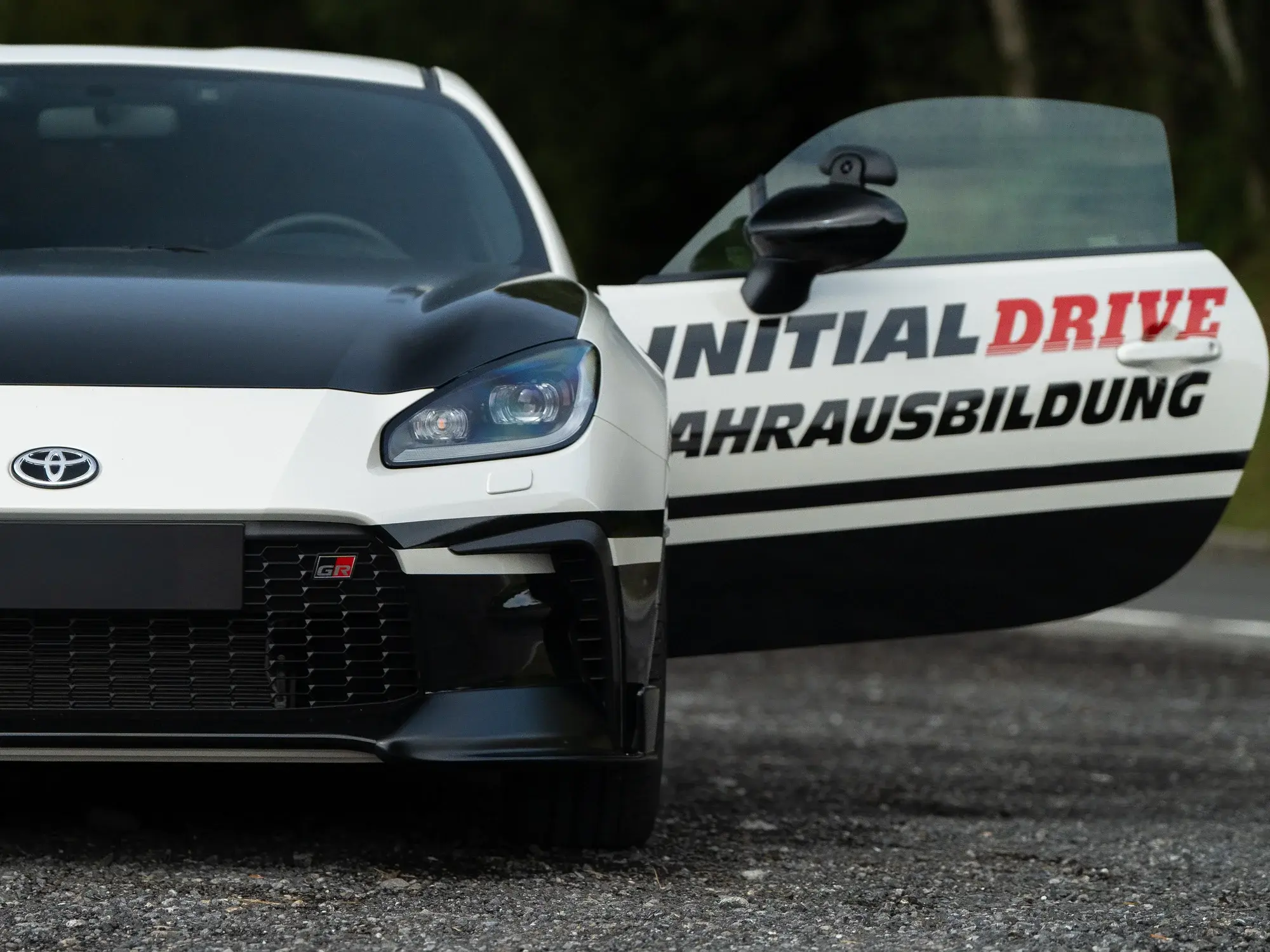Offene Fahrertür des Toyota GR86 mit dem Schriftzug «Initial Drive Fahrausbildung»