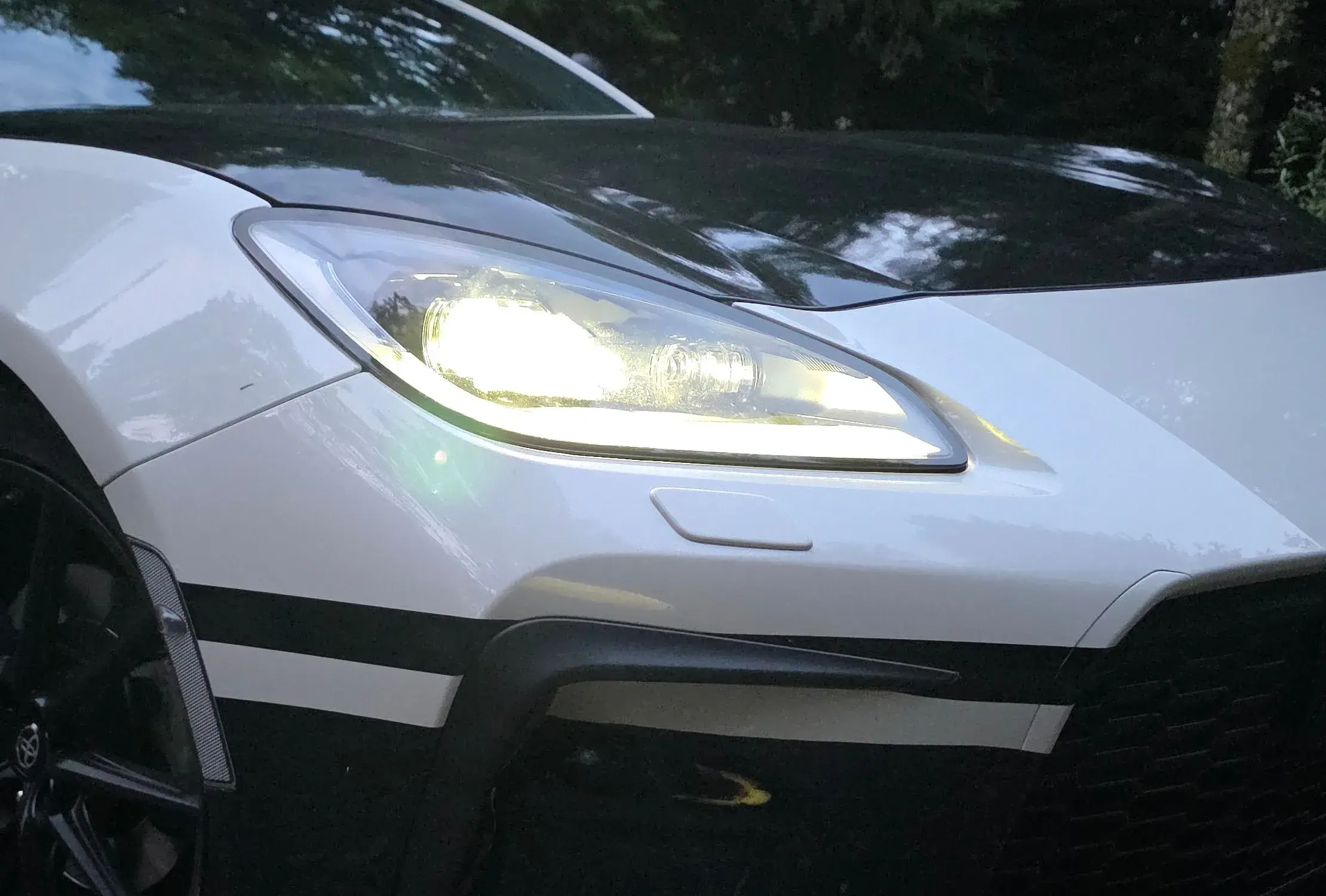 Headlight and front corner of the Initial Drive Toyota GR86 at dusk