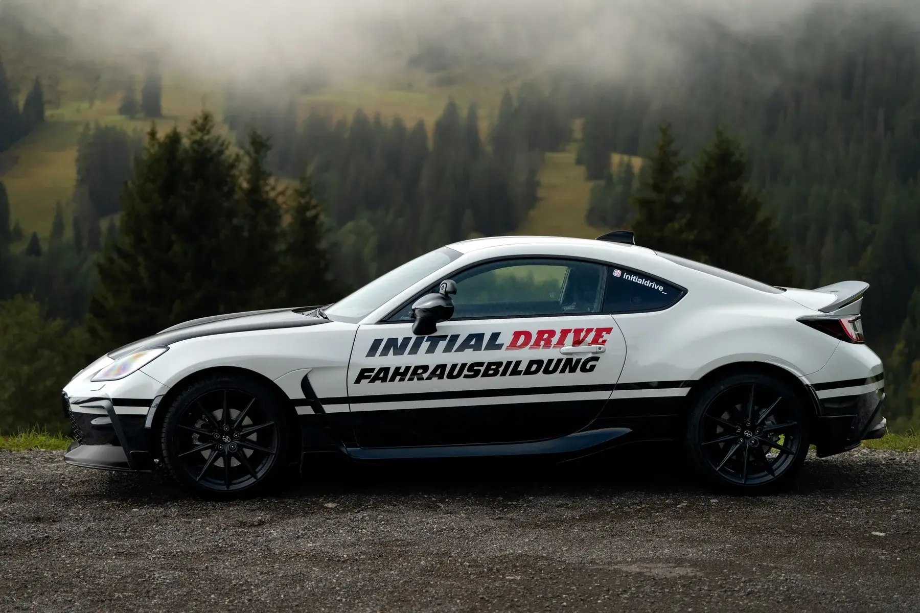 Toyota GR86 von Initial Drive in der Seitenansicht: flach und tief, vor nebligem Bergwald