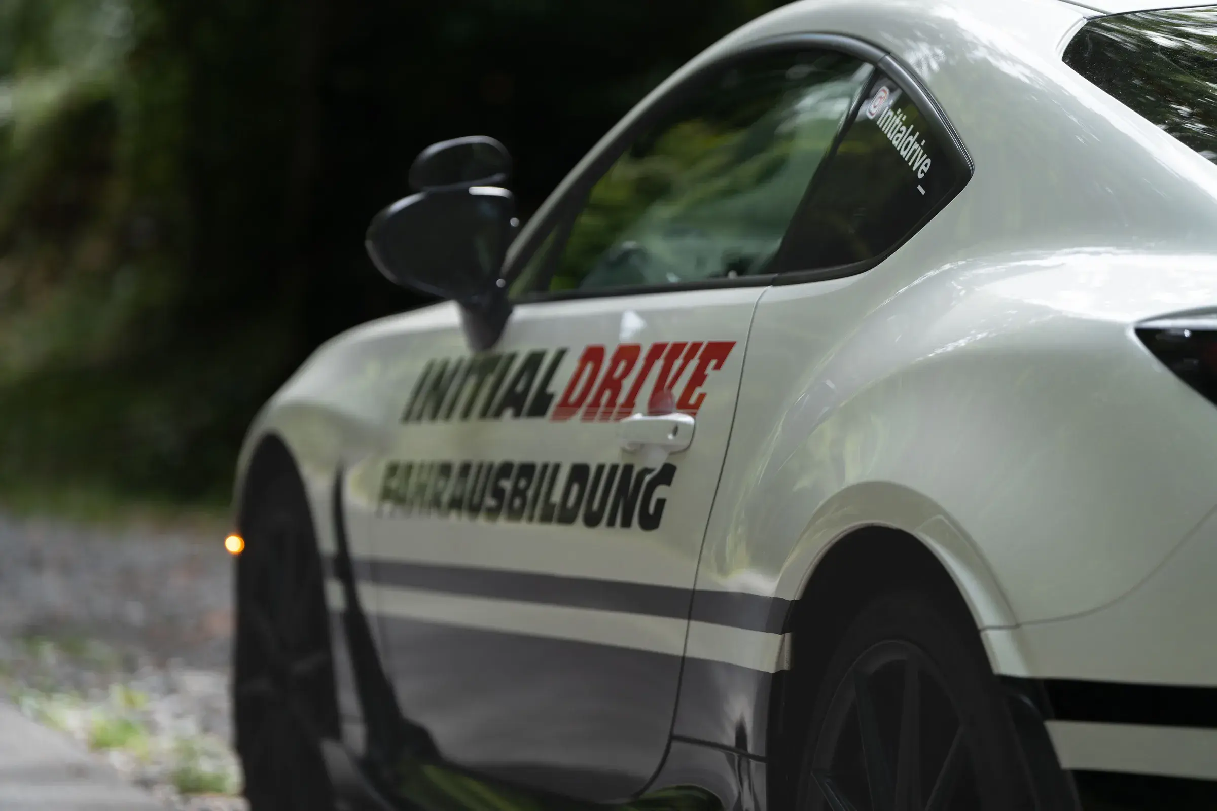 Door of the Initial Drive Toyota GR86 with “Initial Drive Fahrausbildung” lettering, seen from the rear three-quarter view